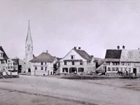 Alte Kirche Amriswil um 1890 (Foto: Jakob Br&uuml;schweiler): mit urspr&uuml;nglichem Turmspitz. Im Vordergrund der beizengekr&auml;nzte Marktplatz, &quot;Suufring&quot; genannt.